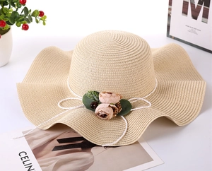 Detailed texture of beige woven straw sun hat with floral bow and wavy brim