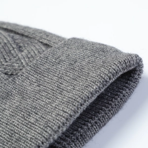 Detail of grey cable knit winter beanie showing thick ribbed texture and warm fabric