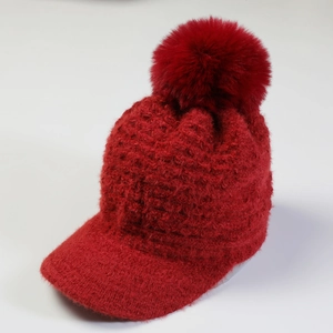 Detailed view of red knit baseball cap with fluffy pom-pom and soft plush texture