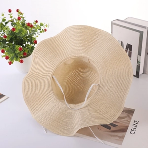 Detail of wavy brim straw hat with windproof rope on minimalist fashion background