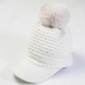 Detailed close-up of a white winter knit peak hat with a fluffy faux fur pom-pom detail