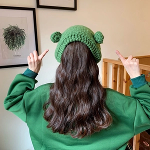 Detail showing the green knitted frog hat with cute ears and coarse crochet texture