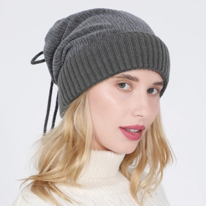 Detail of dark grey knit beanie featuring vertical ribs and an adjustable drawstring