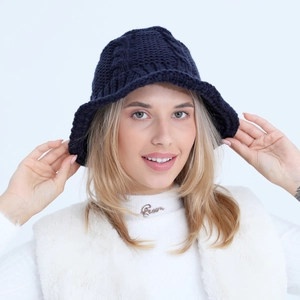 Detail of navy blue knit bucket hat showing thick textured cable pattern and wavy brim