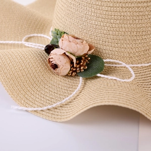 Macro detail of hand-woven straw sun hat with floral decor and leaf accents