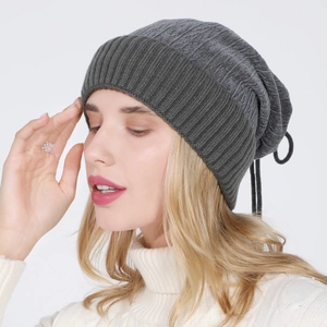 Close-up of deep grey ribbed knit beanie showing thick texture and warm drawstring top
