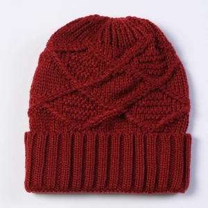 Close-up of deep red knitted beanie featuring a textured diamond pattern and ribbed cuff