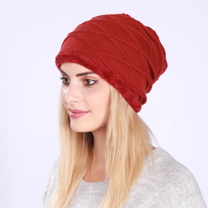 Close-up of deep red knitted beanie featuring faux fur trim and textured rhombus pattern