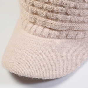 Close-up of beige knit beanie showing thick cable stitch texture and warm plush material