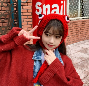 Detailed close-up of handmade red knit frog hat with 3D eyes and thick wool texture