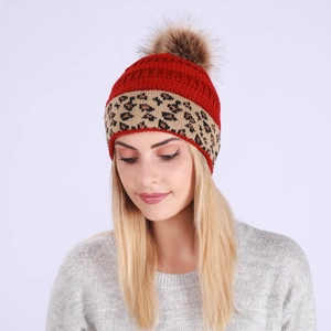 Close-up of winter knit beanie with red leopard pattern and large faux fur pom-pom detail