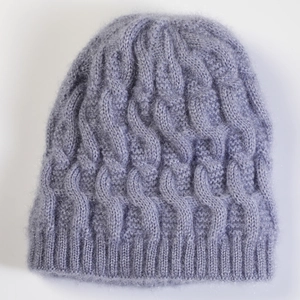 Detail of lavender purple cable knit beanie showing thick wool texture and ribbed edge