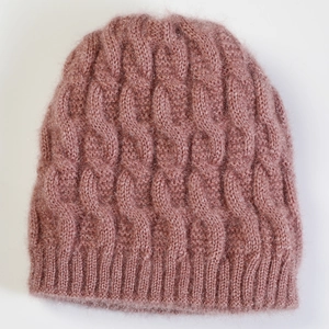 Macro detail of soft dusty pink knitted beanie showing cable knit texture and ribbing