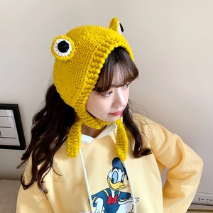 Detailed knit texture of a yellow frog earflap hat with large decorative eyes