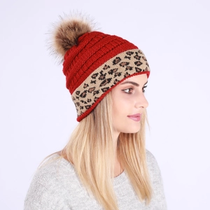 Detail of red cable knit winter beanie with leopard print brim and fluffy fur pompom