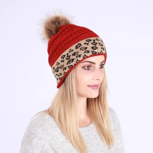 Detailed close-up of a red knit beanie featuring a leopard print cuff and faux fur pom-pom