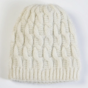Macro detail of white cable knit pattern and soft texture on women's winter beanie hat