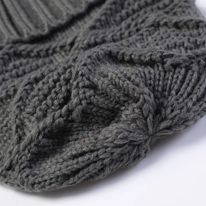 Macro detail of dark grey chunky knit beanie with diamond pattern and cable stitching