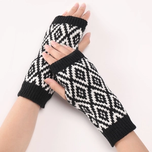 Detail van zwart-witte gebreide armwarmers met ruitpatroon en geribbelde zoom