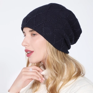 Detail view of dark blue diamond-patterned knit beanie for women on model