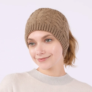 Close-up of caramel cable knit ponytail beanie showing the top opening and warm texture