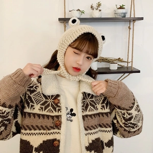 Detailed knit of beige frog earflap hat with decorative eyes and chin straps