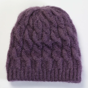 Detailed close-up of dark purple cable-knit wool texture and ribbed cuff of the beanie