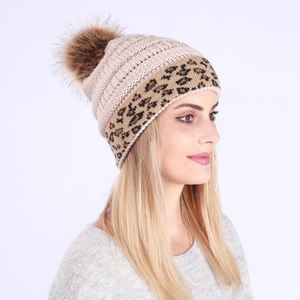 Close-up of knit winter beanie with leopard print trim and fluffy faux fur pompom