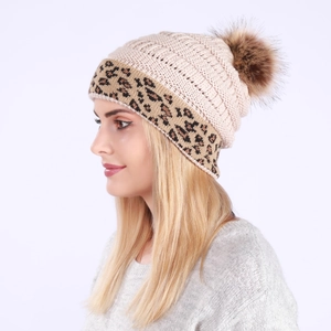 Close-up of beige chunky knit beanie with leopard print cuff and faux fur pompom detail