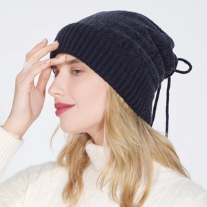 Detail of navy knit beanie with ribbed brim and drawstring back on a model