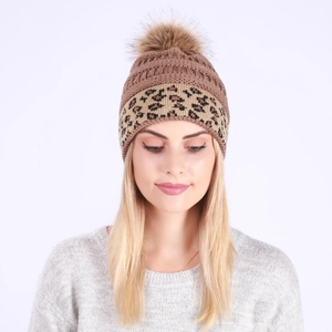 Close-up of winter knit beanie with leopard print band and brown faux fur pom pom detail