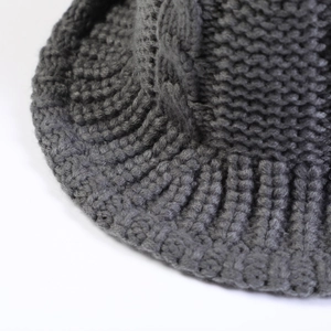 Close-up of dark grey cable knit beanie showing thick thread texture and ribbed edge detail