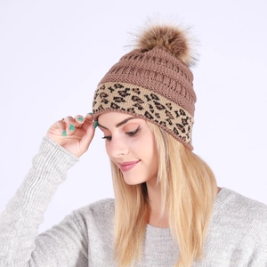 Detail of chunky knit winter beanie featuring leopard print cuff and faux fur pom pom decoration