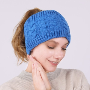 Close-up of blue cable knit headband featuring top ponytail hole for winter warmth