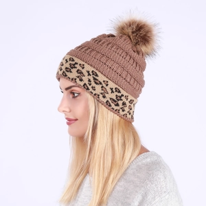 Detail of warm cable knit hat with leopard print cuff and large faux fur pom-pom