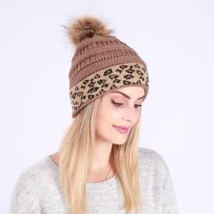 Detail view of the soft faux fur pom-pom and thick knitted texture of the winter hat