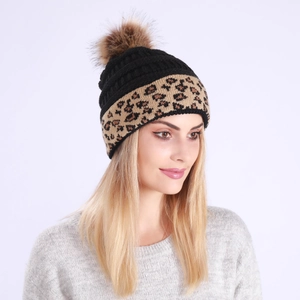 Close-up of black cable knit beanie with leopard print cuff and faux fur pom-pom