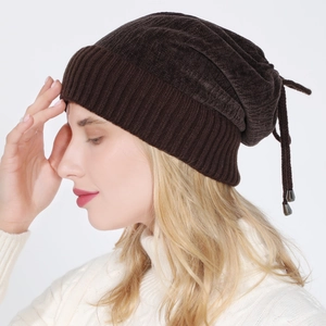 Detail of dark brown knit beanie featuring ribbed cuff and adjustable drawstring with metal charm
