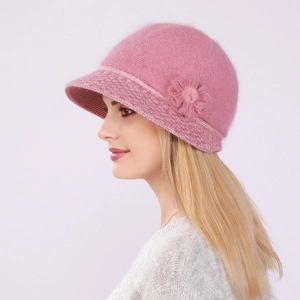 Detail of pink knitted rabbit fur hat featuring a floral accent and soft winter lining