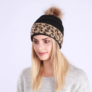 Detail view of winter knitted beanie with leopard pattern and large brown faux fur pom-pom