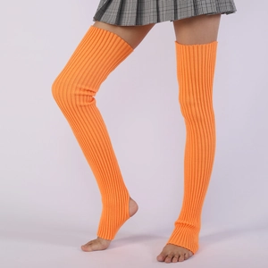Close-up of bright orange ribbed knit stirrup leg warmers on model for yoga and dance