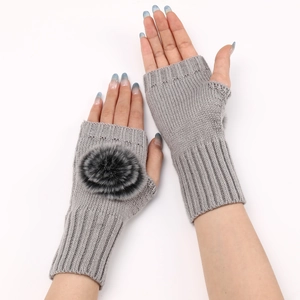 Détail de mitaines en tricot gris avec pompon décoratif et poignets en maille côtelée