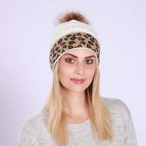 Close-up of white cable knit beanie with leopard print band and brown faux fur pom-pom