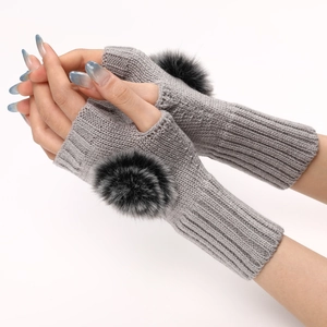 Détails de la maille des mitaines grises ornées de grands pompons noirs pour l'hiver
