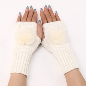 Détail de la texture en maille de gants blancs sans doigts avec grands pompons en fourrure