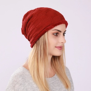 Detail of red knitted beanie with plaid texture and thick faux fur trim for cold weather
