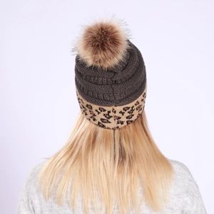Detail of dark grey knit beanie with leopard print rolled brim and soft brown faux fur pom