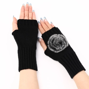 Détail de mitaines en tricot noir avec un pompon en fausse fourrure douce et poignets côtelés