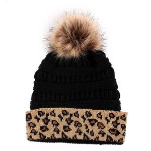 Detail of winter knit hat with fluffy pom-pom and stylish leopard print cuff