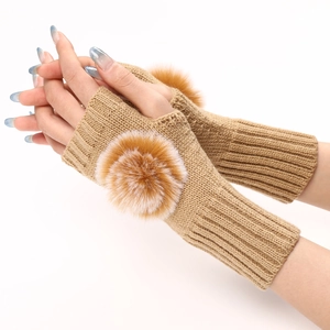Détail de mitaines en tricot marron clair avec des pompons en fausse fourrure bicolores
